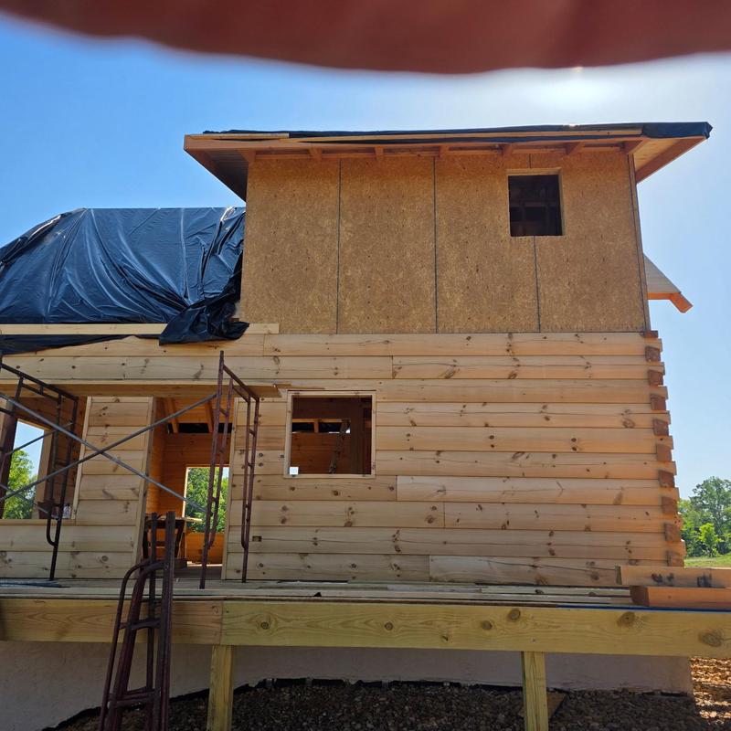 Wooden log siding installation on house under construction Wooden log siding installation on house under construction