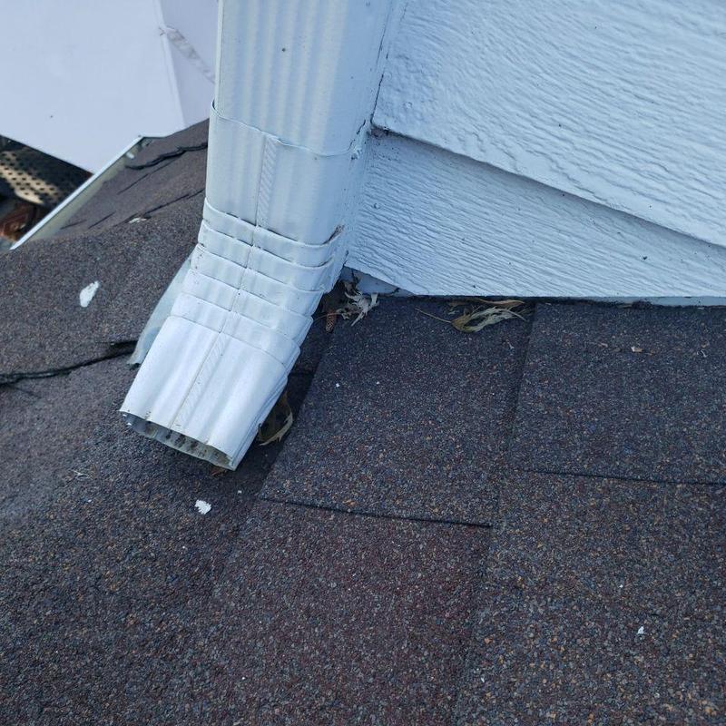 Roof shingles and downspout connection on house corner Roof shingles and downspout connection on house corner