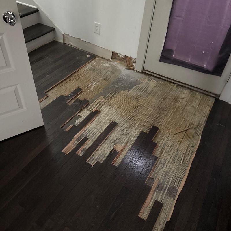 Hardwood floor peeling and water damage near door
