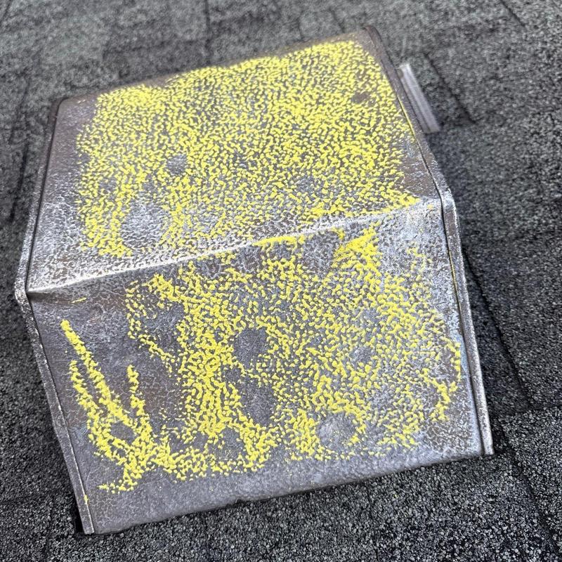 Metal roof vent with hail damage marked in yellow