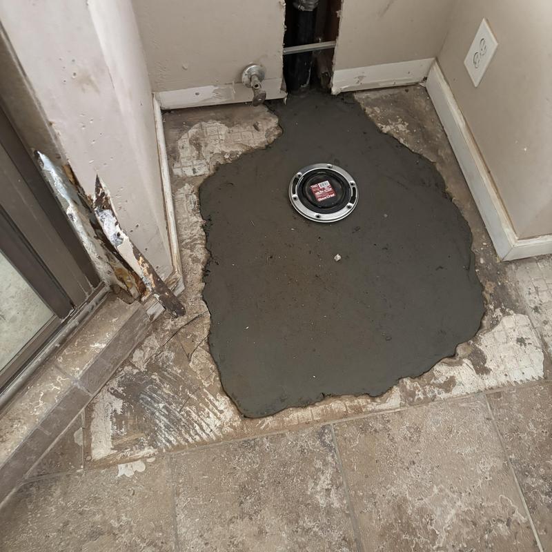 Toilet flange with fresh cement patch in bathroom floor Toilet flange with fresh cement patch in bathroom floor