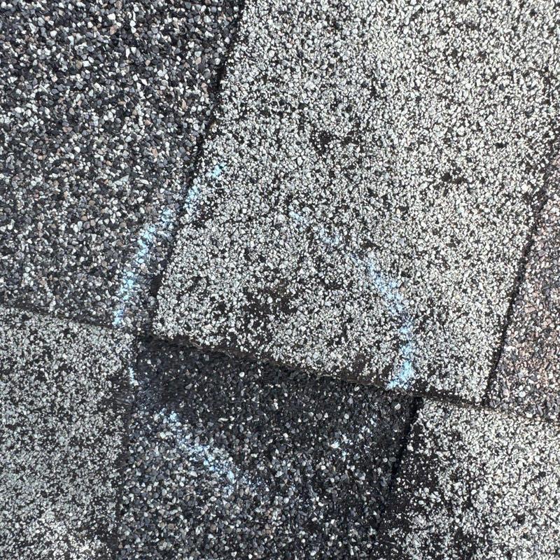 Hail-damaged asphalt roof shingles with chalk markings