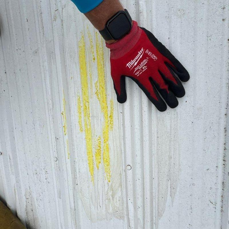 Metal roof hail damage inspection with gloved hand