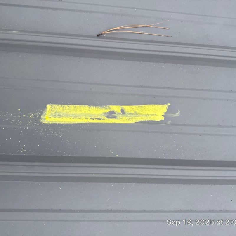 Metal roofing panel with yellow hail damage mark