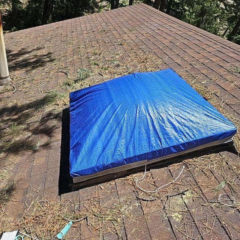 Shingle roof with blue tarp over skylight opening Shingle roof with blue tarp over skylight opening