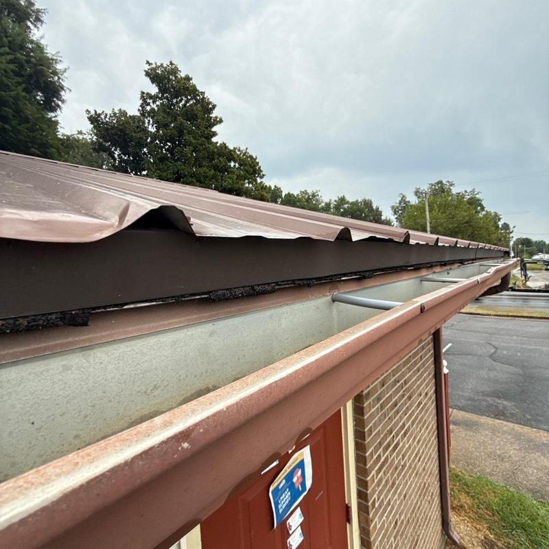 Metal roofing edge with hail damage on commercial building