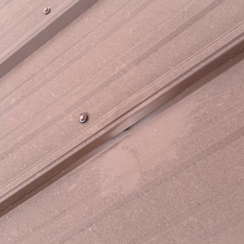Metal roofing panel with hail damage dent