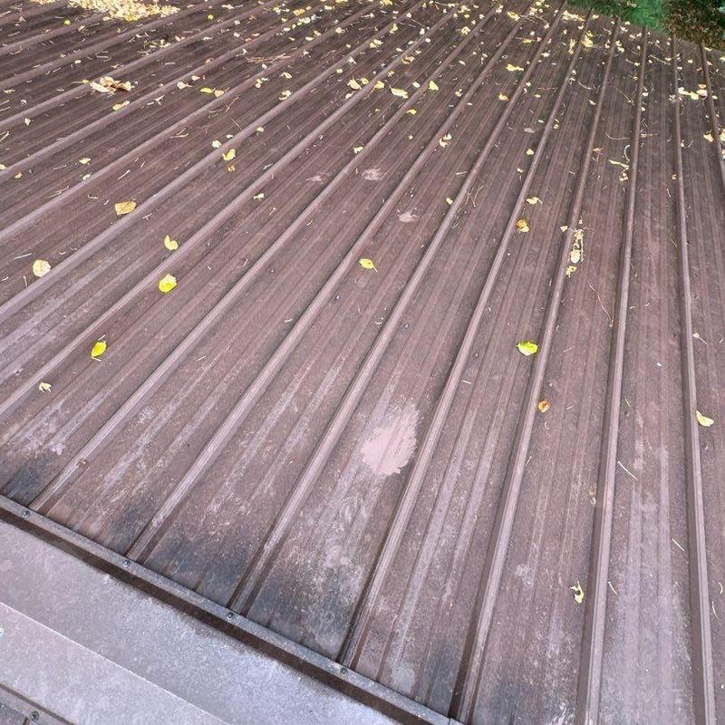 Metal roofing panels with hail damage and debris