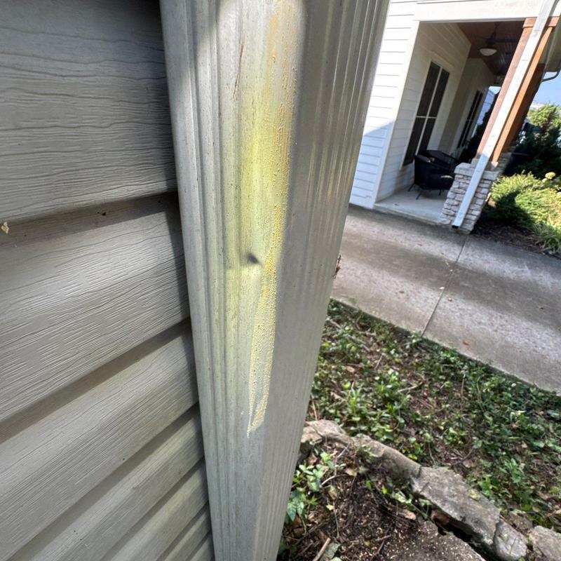 Metal gutter with dent and discoloration on house exterior