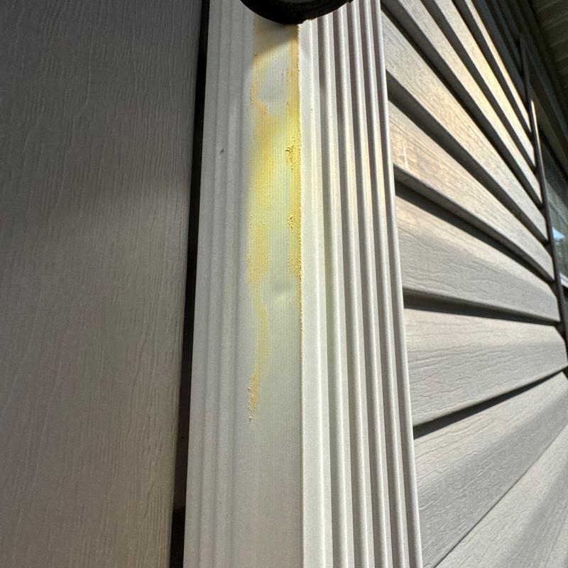 Vinyl siding trim with yellow stain on siding panel