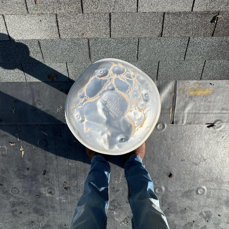 Metal roof vent cap with hail damage on shingles