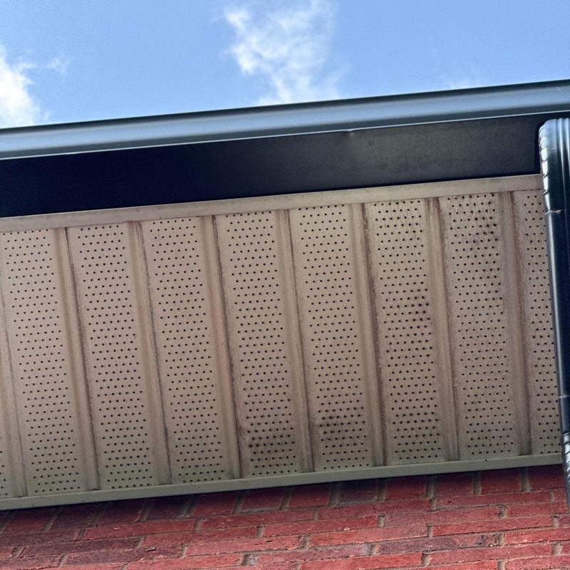 Perforated soffit panels with gutter and brick wall