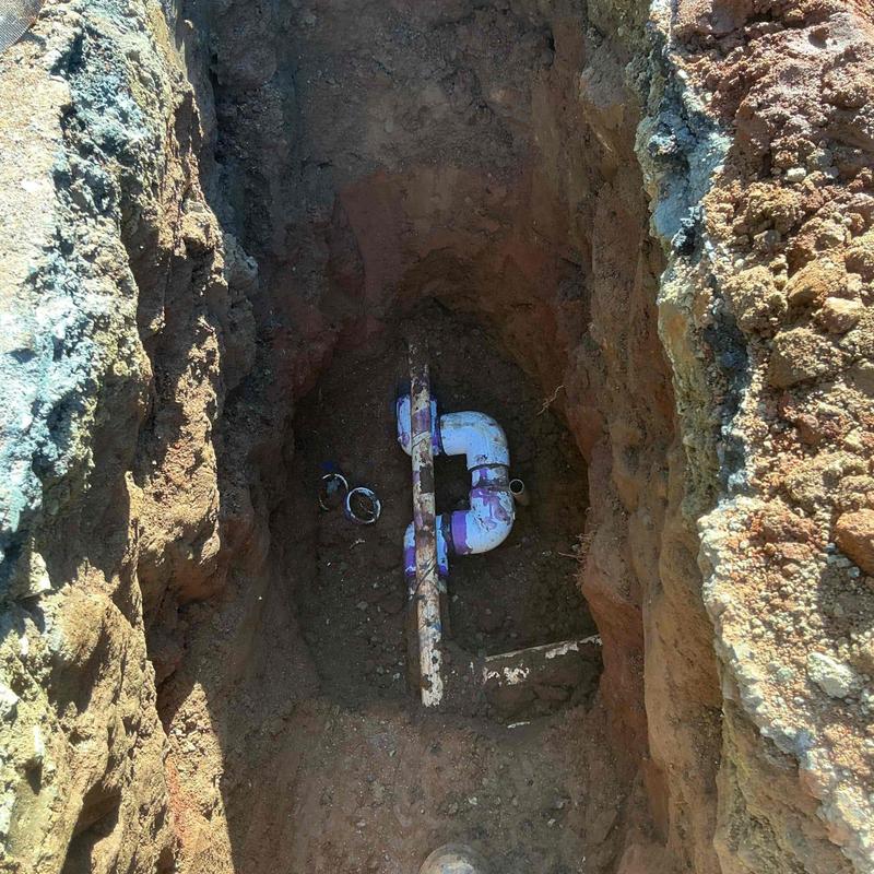 PVC main pipe in excavated trench with repair fittings