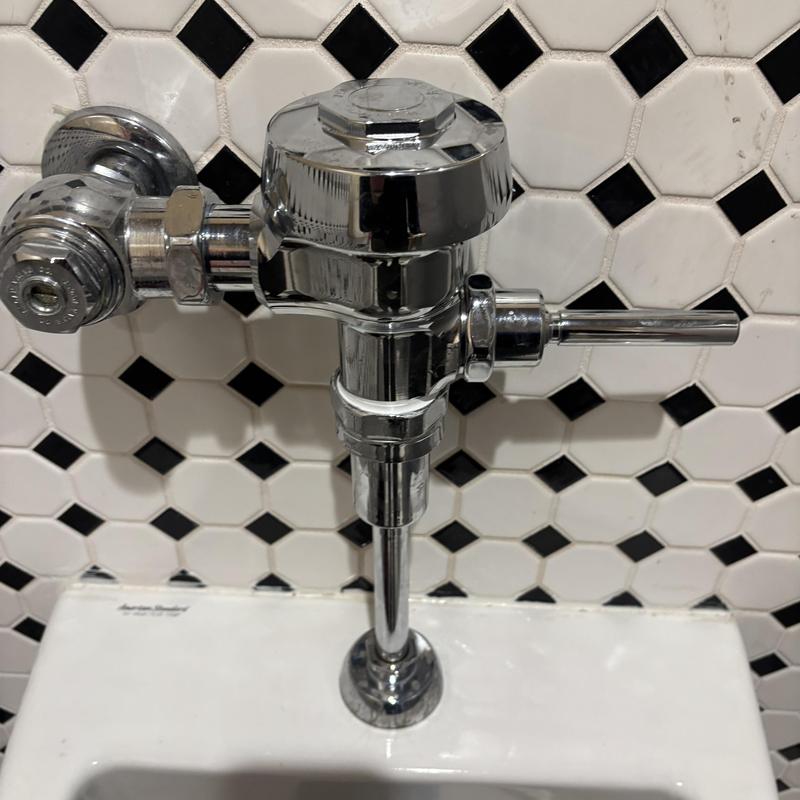 Men's urinal Sloan flush valve on tiled wall Men's urinal Sloan flush valve on tiled wall