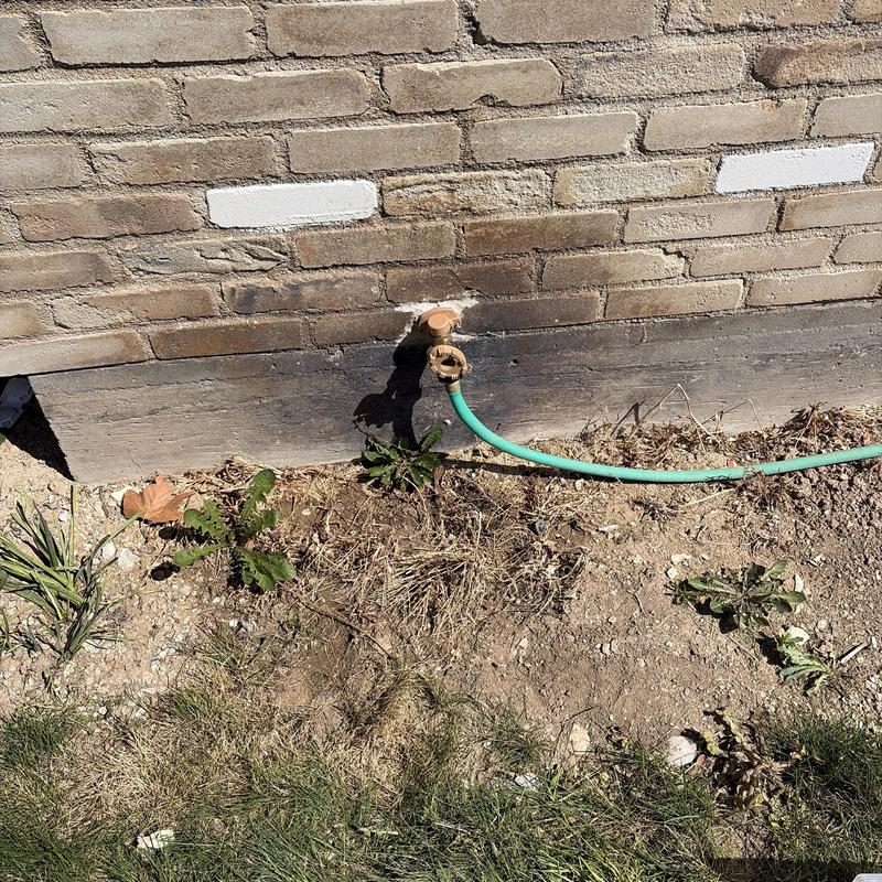 Front hose bib installation with garden hose attached outdoors