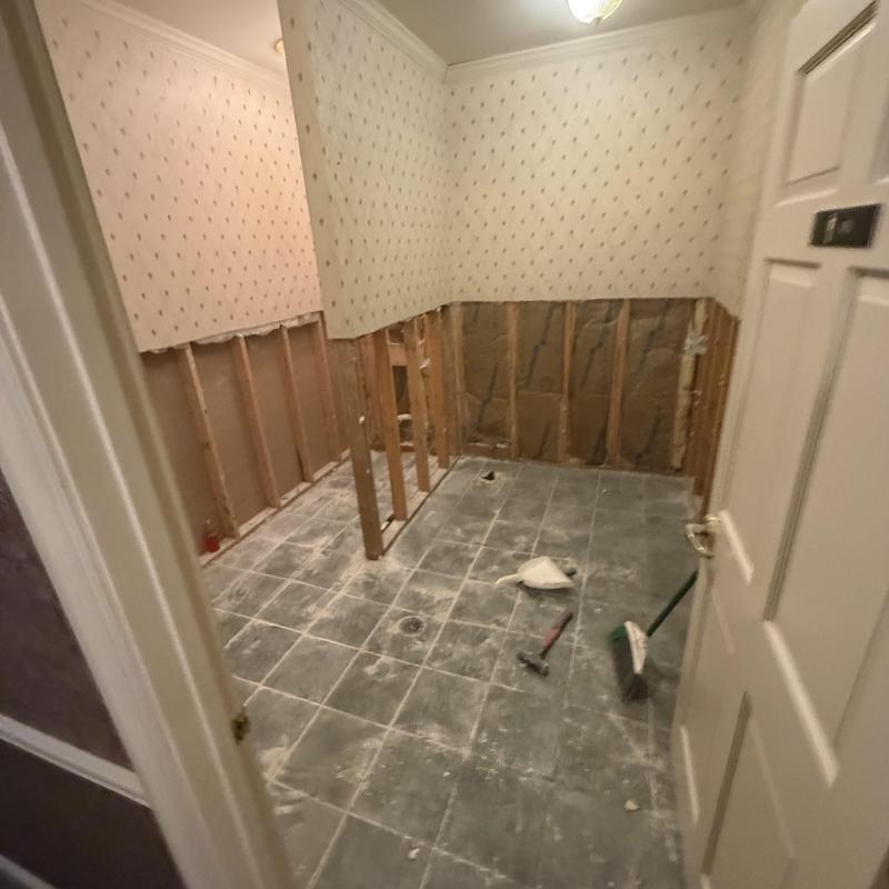 Restroom wall demolition with exposed insulation and tools
