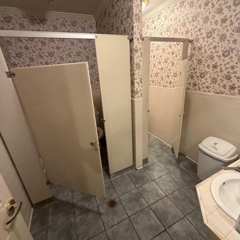 Bathroom stall demolition with floral wallpaper and tiled floor