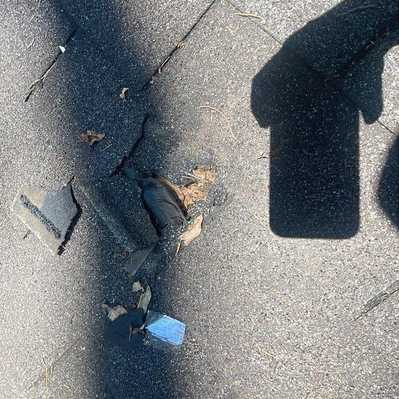 Asphalt shingle roof damage with puncture and debris