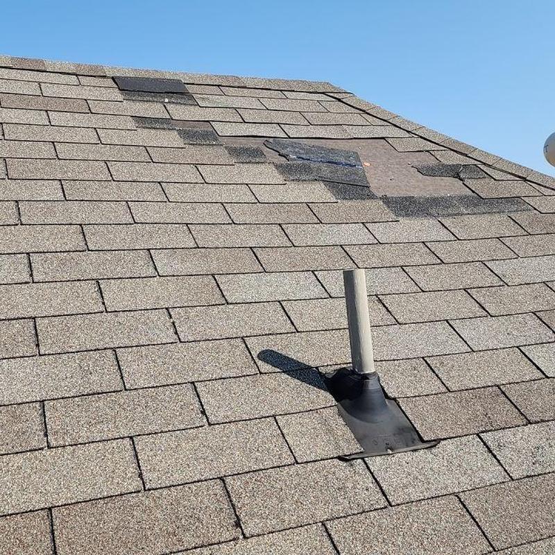 Asphalt shingles with partial wind damage on roof