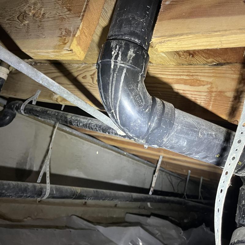 Black PVC drain pipe with elbow joint under floor joists