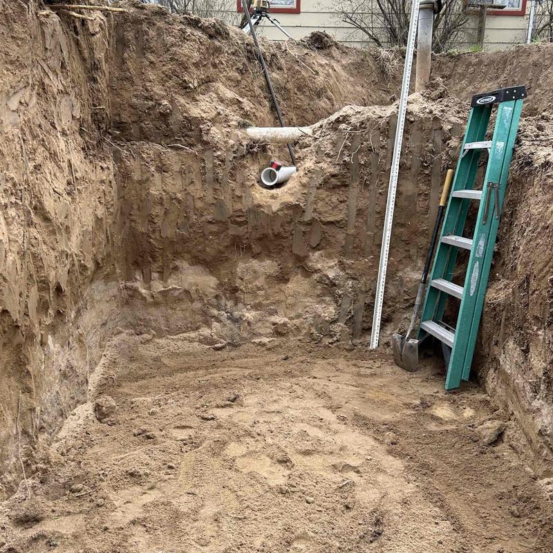 Septic tank access excavation with plumbing pipes