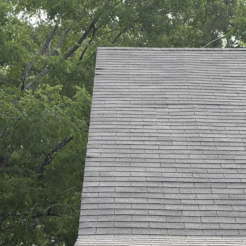 Asphalt shingle roof with visible damage near ridge