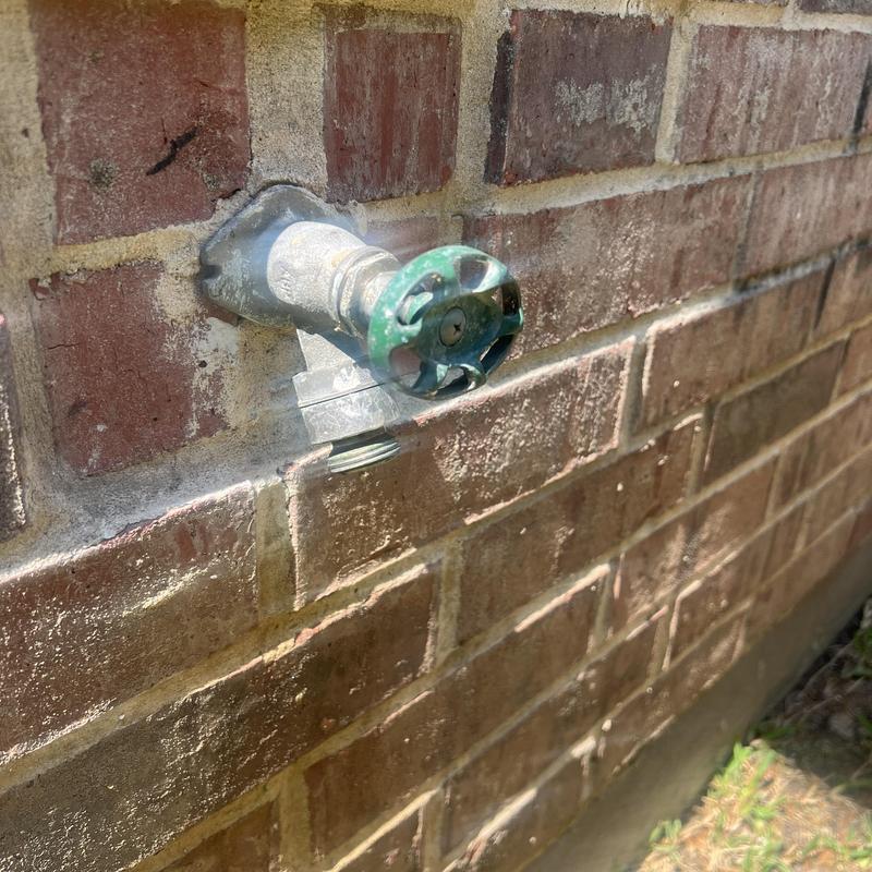 Outdoor hose bib faucet mounted on brick wall