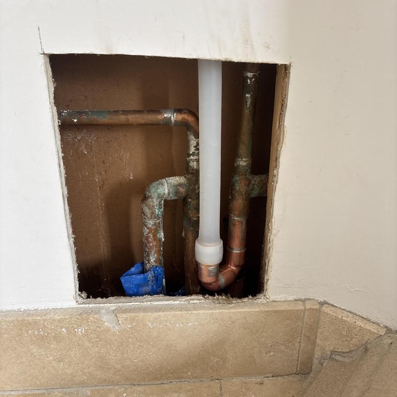 Copper plumbing pipes with slab leak repair access hole Copper plumbing pipes with slab leak repair access hole