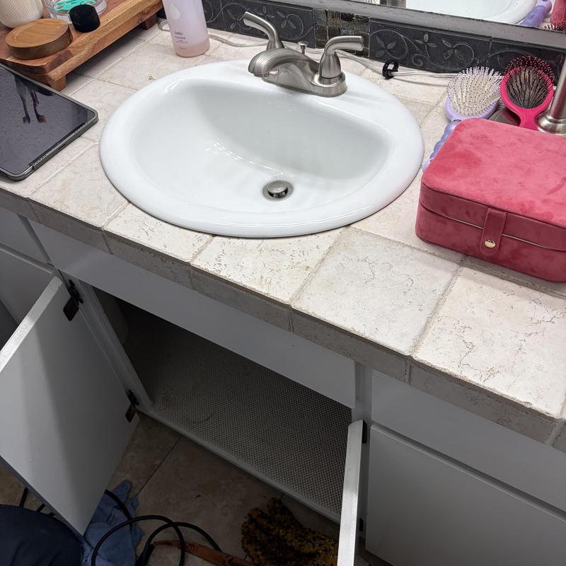 Bathroom sink faucet and drain with open cabinet below