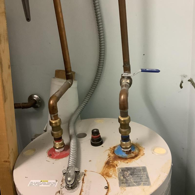 Electric water heater piping with valve and rust spots