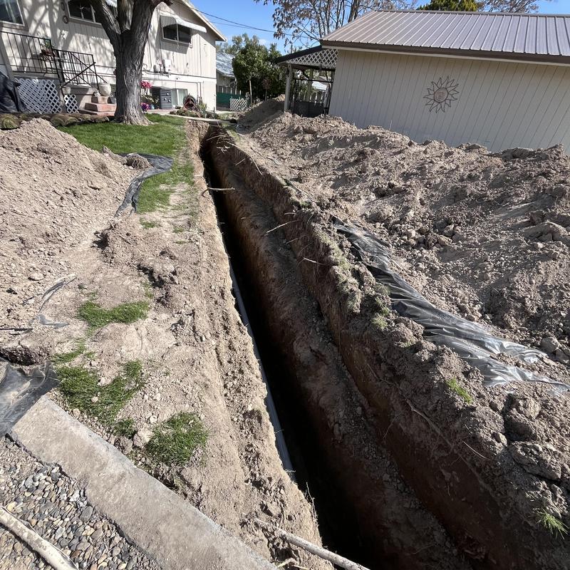 Sewer pipe trench excavation alongside residential yard