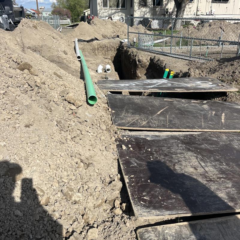 City sewer main trench with green sewer pipe installation