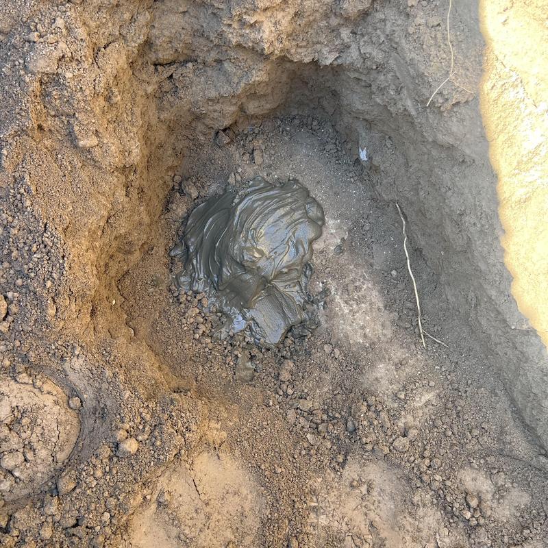 Old sewer tap capped with sealant in soil hole
