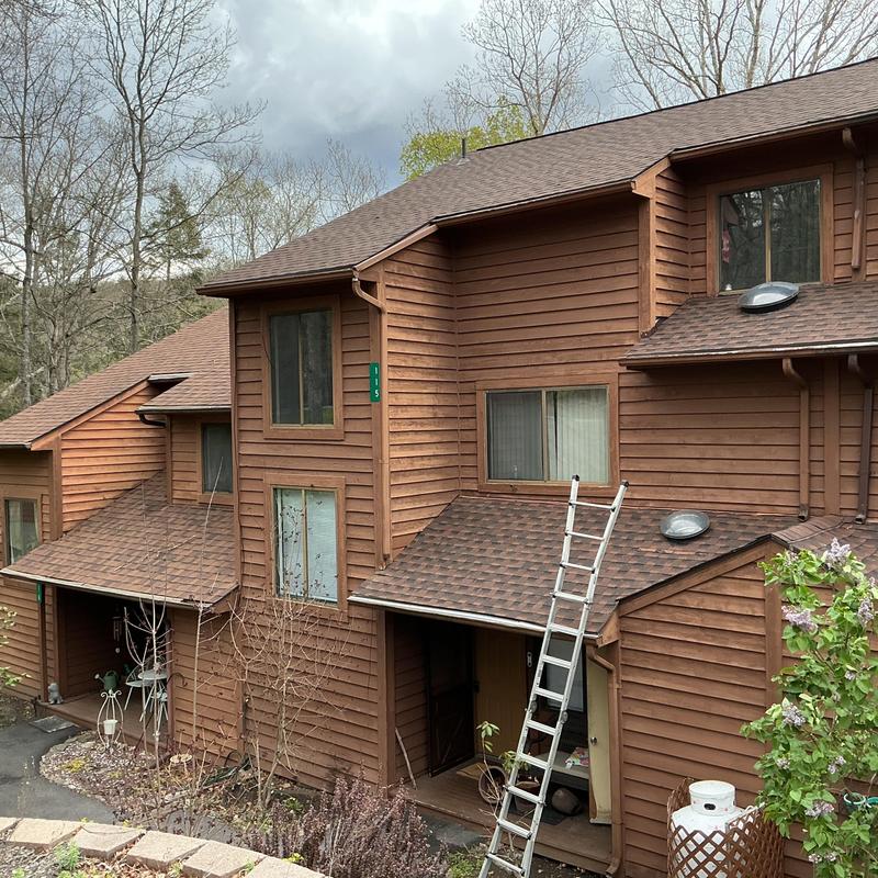 Asphalt shingle roof installation on brown wood siding house Asphalt shingle roof installation on brown wood siding house