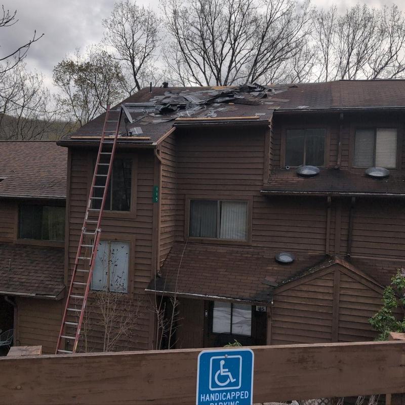 Damaged roof shingles with ladder on brown townhouse Damaged roof shingles with ladder on brown townhouse