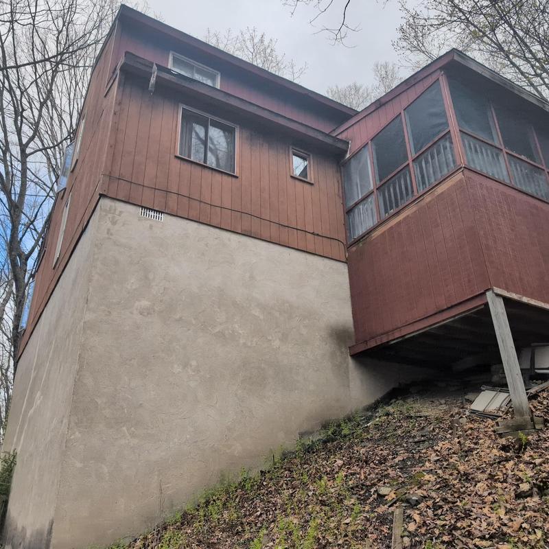 Wooden siding and screened porch exterior on hillside home Wooden siding and screened porch exterior on hillside home