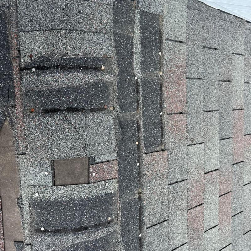 Storm-damaged asphalt roof shingles with nails