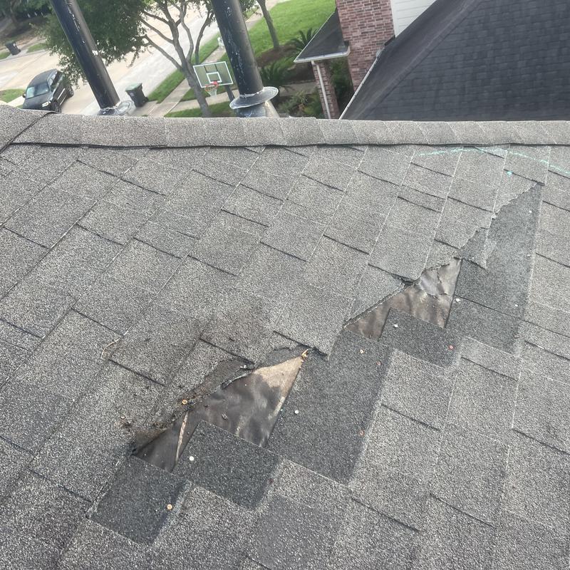 Asphalt roof shingles with visible damage and missing pieces