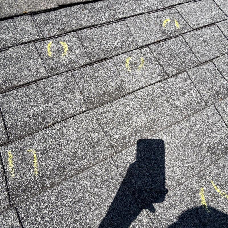 Asphalt shingles with hail damage marked in yellow