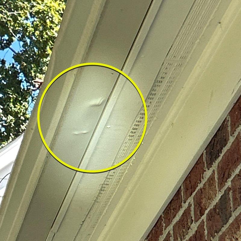 Roof soffit hail dents inspection with yellow circle highlight