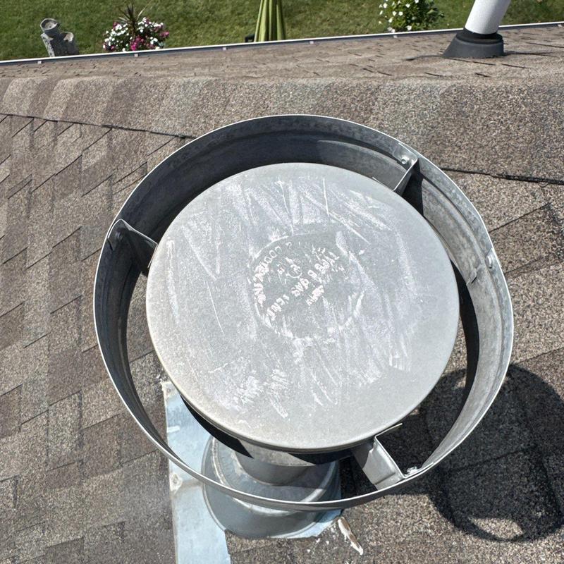 Metal chimney cap on asphalt shingle roof with flashing