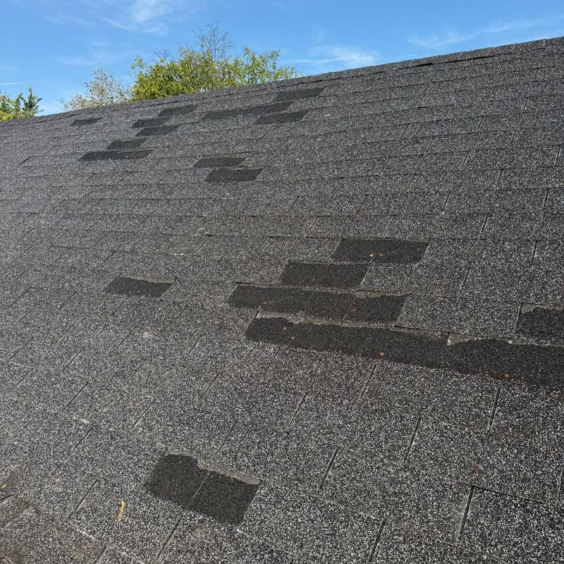 Asphalt shingle roof with visible hail damage patches