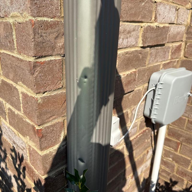 Downspout dent with nearby junction box on brick wall