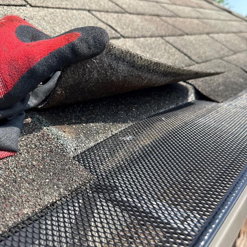 Roof shingles inspection showing hail damage and gutter guard