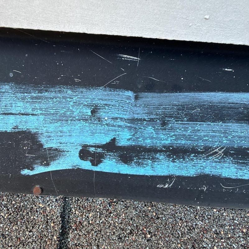 Metal flashing with blue marking and surface scratches