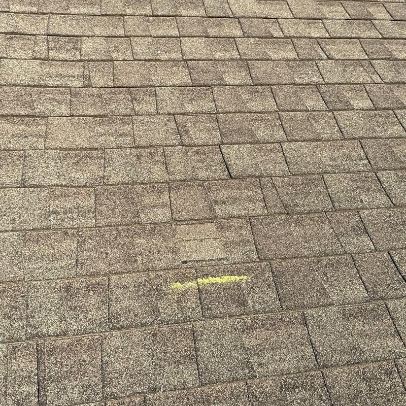 Asphalt roof shingles with marked hail damage