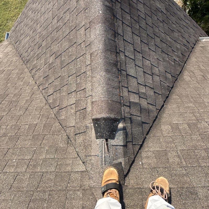 Asphalt shingle roof ridge with visible hail damage
