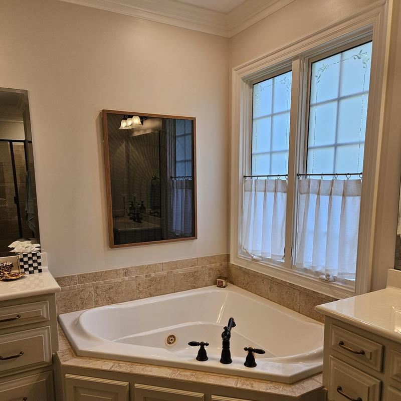 Corner bathtub with black faucet and beige tile surround