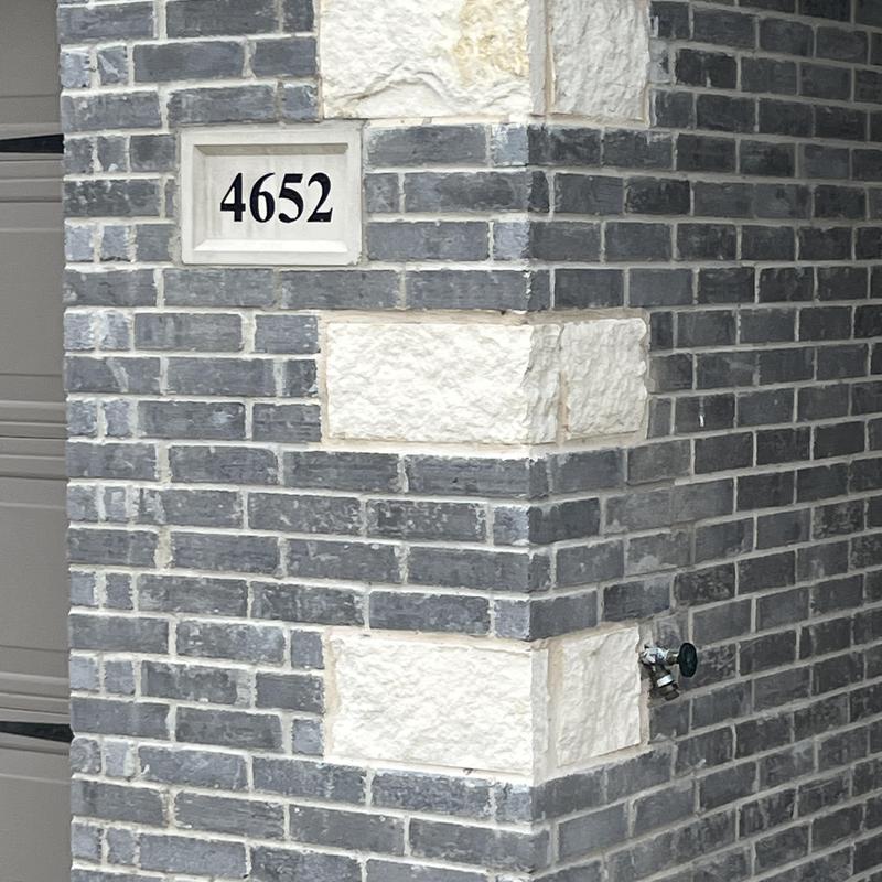 Brick and stone exterior corner with house number plaque