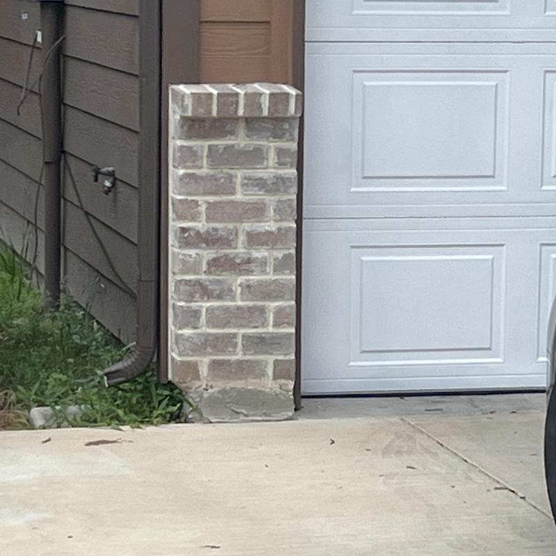Garage door panel next to brick pillar and driveway